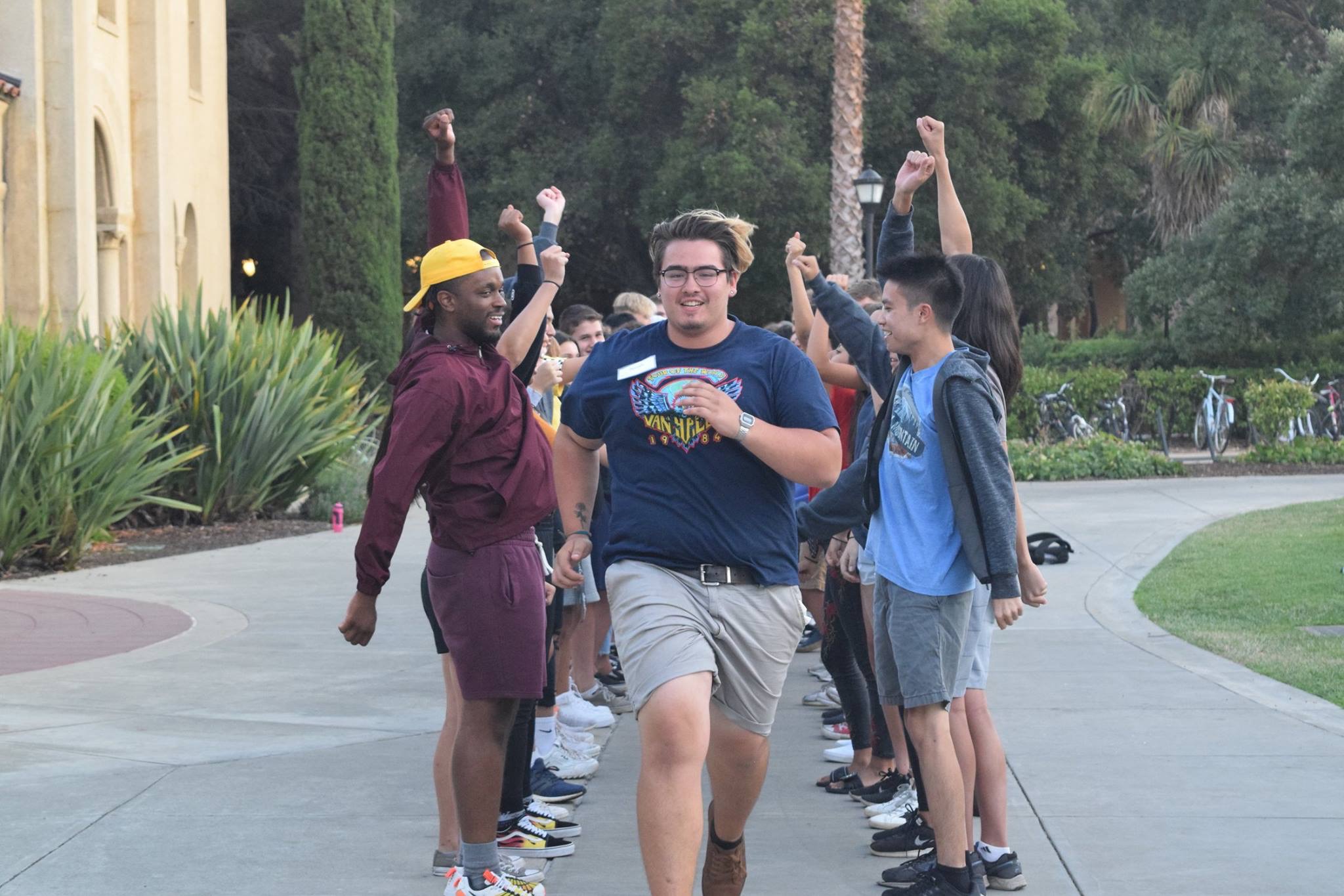 A participant running past a finish line with others cheering him on